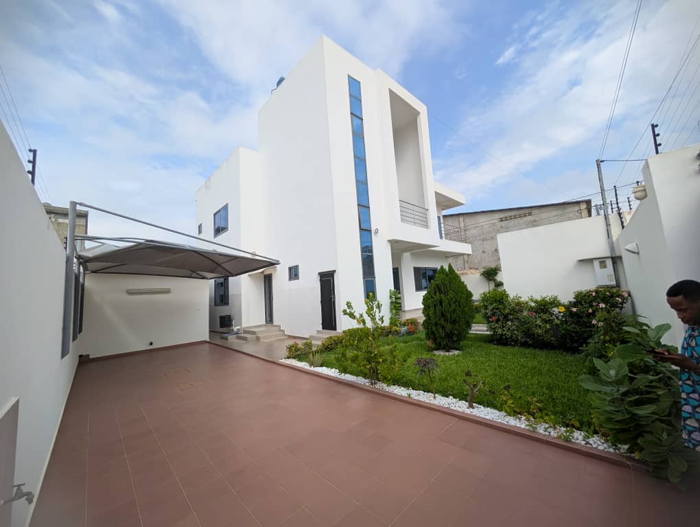 Villa blanche livrée par LMG, avec sa cour carrelée et son jardin